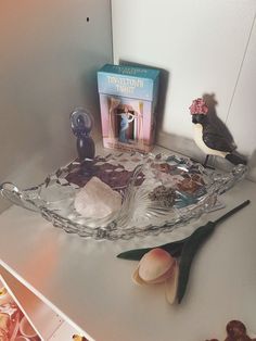 there is a glass bowl on the counter with shells and other items around it,