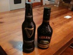 two beer bottles sitting on top of a wooden counter