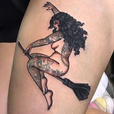 a tattooed woman sitting on top of a broom