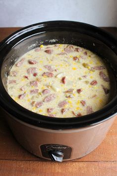 a crock pot filled with ham and cheese on top of a wooden countertop