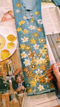 someone is painting flowers on an old pair of jean pants with yellow and white paint