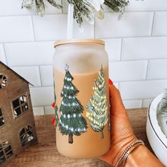 a hand holding a glass with christmas trees on it