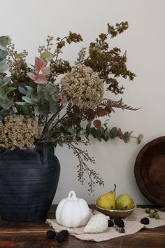 an arrangement of flowers and fruit on a table