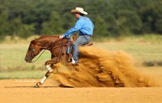 a man riding on the back of a brown horse while kicking up dirt in front of him