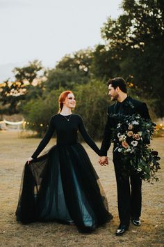 a man and woman dressed in black holding hands