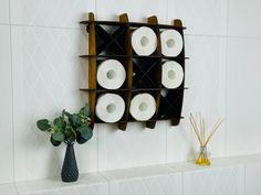 a shelf with several rolls of toilet paper on it next to a vase filled with flowers