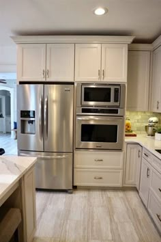 a kitchen with white cabinets and stainless steel appliances