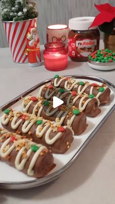 chocolate covered pretzels on a white plate with christmas decorations and candy in the background