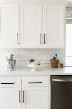 a kitchen with white cupboards and appliances on the counter top, next to a dishwasher