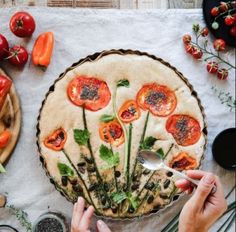 a person cutting tomatoes on top of a pie