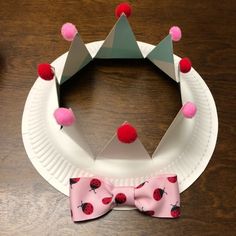 a paper plate with a pink bow tie and a crown made out of paper plates