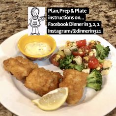 a white plate topped with fried fish and salad next to a bowl of dressing on top of a counter