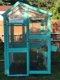 a small green house sitting in the middle of a yard