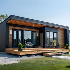 a small house with wooden deck and black siding on the outside, surrounded by green grass