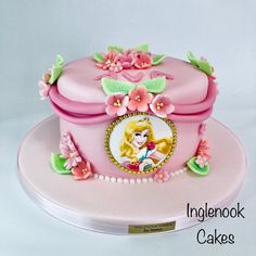 there is a pink cake decorated with flowers and a princess's face on it