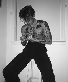 a man with tattoos is sitting on a stool