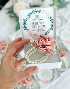 a person holding up a card with a flower on it in front of some flowers