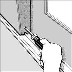 a hand holding a screwdriver near a window