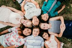 a group of children laying on the ground in a circle smiling and looking at the camera