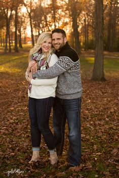 a man and woman hugging in the fall leaves