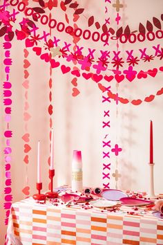 the table is decorated with pink and red paper hearts hanging from it's ceiling