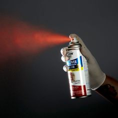 a person holding a spray can with red light coming from it