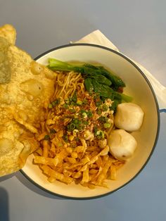 a bowl filled with noodles and vegetables next to some tortilla chips on a table