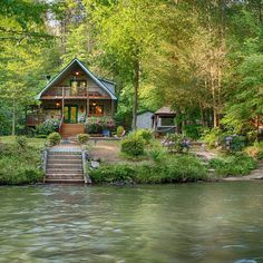 a house sitting on top of a river surrounded by trees