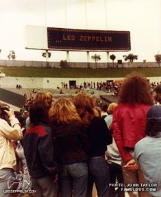 a group of people standing in front of a large screen at a soccer stadium with the words led zepplin on it