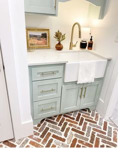 a kitchen sink sitting under a mirror next to a doorway with a painting on the wall