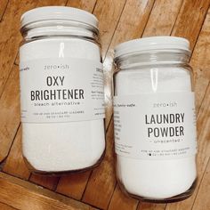 two jars of laundry powder sitting on top of a wooden floor next to each other