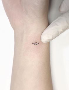 small saturn tattoo on the wrist