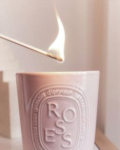 a lit matchstick sticking out of a cup with the word roses written on it