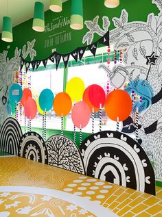 an artisticly decorated room with balloons on the ceiling and large wall mural in the background