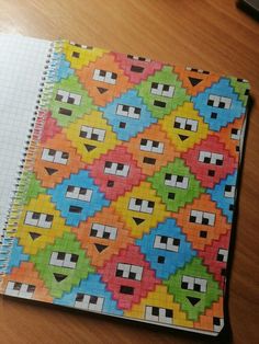 a notebook covered in colorful squares and shapes on a wooden table next to a computer mouse