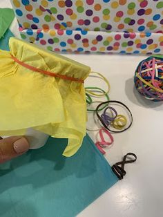 someone is making something out of tissue paper and wrapping it around with string, scissors and other crafting supplies