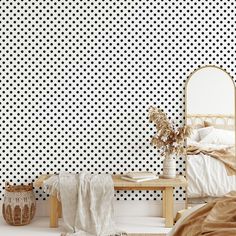 a bedroom with black and white polka dot wallpaper, a wooden bench, and a bed