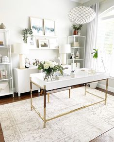 a living room with white furniture and flowers on the coffee table in front of a window