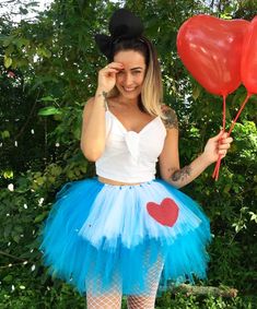 a woman wearing a blue tutu and heart shaped balloons in front of her face