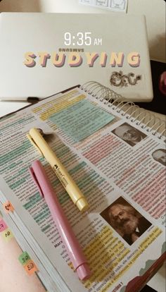 a pink pen sitting on top of an open book