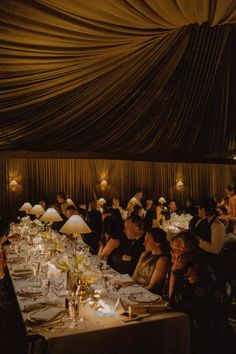 a group of people sitting at tables in a room with white tablecloths on the walls