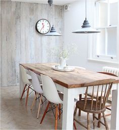 a dining room table with chairs and a clock on the wall