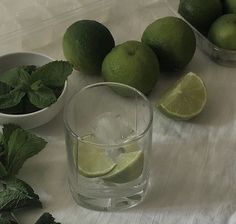 limes, mint and water on a white tablecloth with bowls of limes