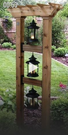 a wooden structure with lanterns hanging from it's sides in front of a yard