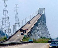 cars are driving on the road near an overpass and power lines in the background