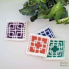 three crocheted coasters sitting on top of a table next to a potted plant