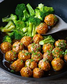 broccoli and meatballs are being cooked in a skillet with a spoon