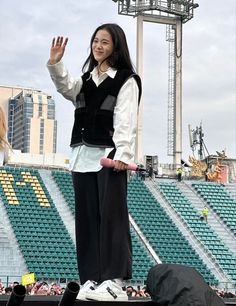 a woman standing on top of a stage waving