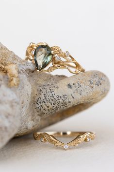 two gold rings sitting on top of a rock next to a stone and diamond ring