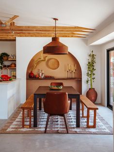 a kitchen with an oven and dining table in the center, surrounded by potted plants